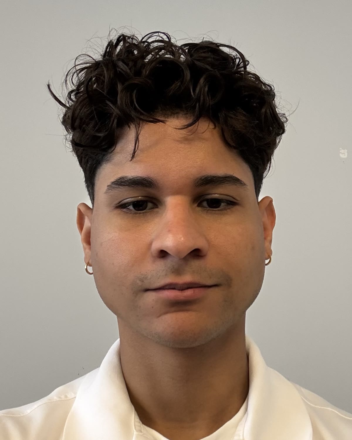 Amel Perez Cavallo, head and shoulders, in a white polo against a grey wall